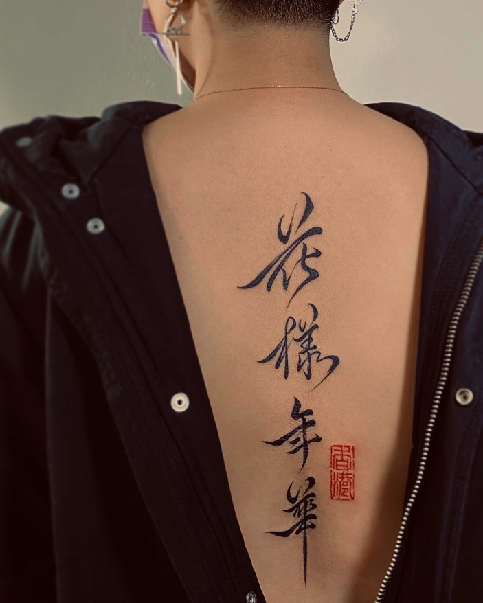 Person wearing a black jacket with a visible tattoo on their back featuring Chinese characters.