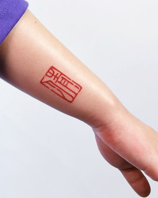 Red tattoo on a person's arm against a light gray background