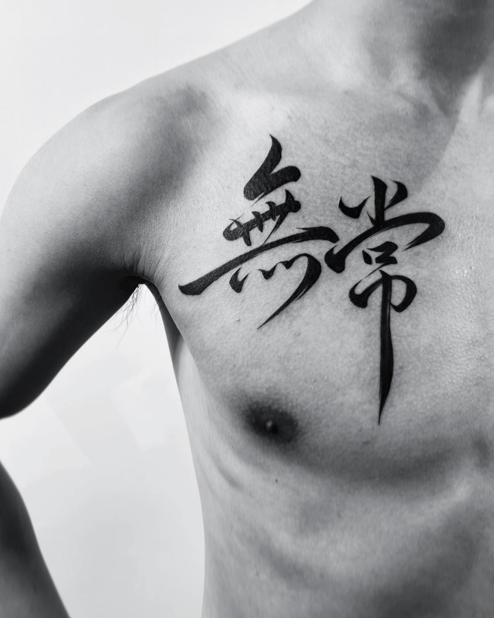 Man with black calligraphy tattoo on chest against a light gray background